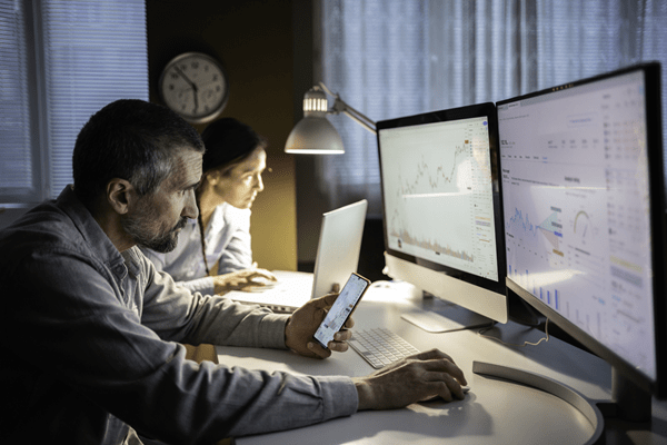 Two people working on two computer screens