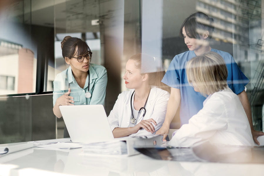 A group of healthcare professionals working together on a computer.