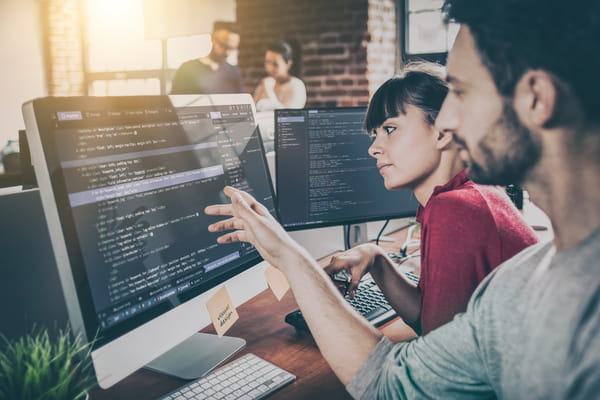 Colleagues inspecting code on a computer together.