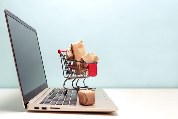 Mini shopping cart sitting on a laptop.