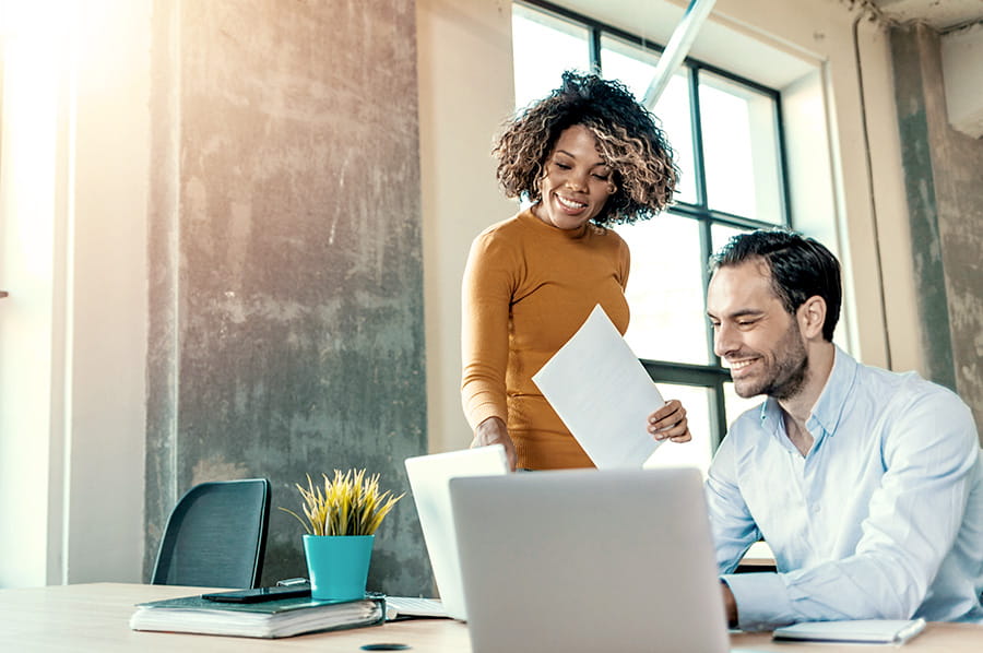 A woman and a man looking at a laptop device