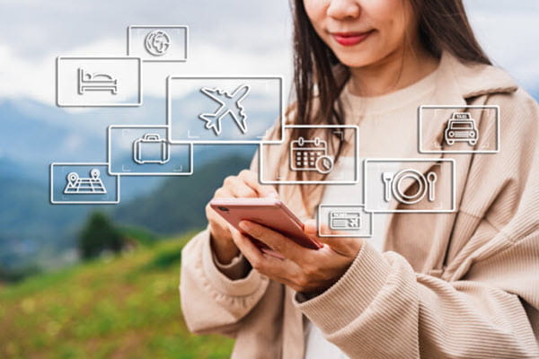 A woman using her phone with multiple travel icons.