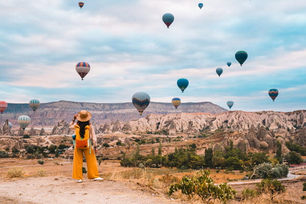 A woman watching a field of hot air balloons take off.