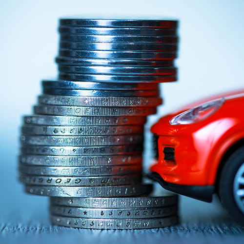 A stack of coins by a toy car.