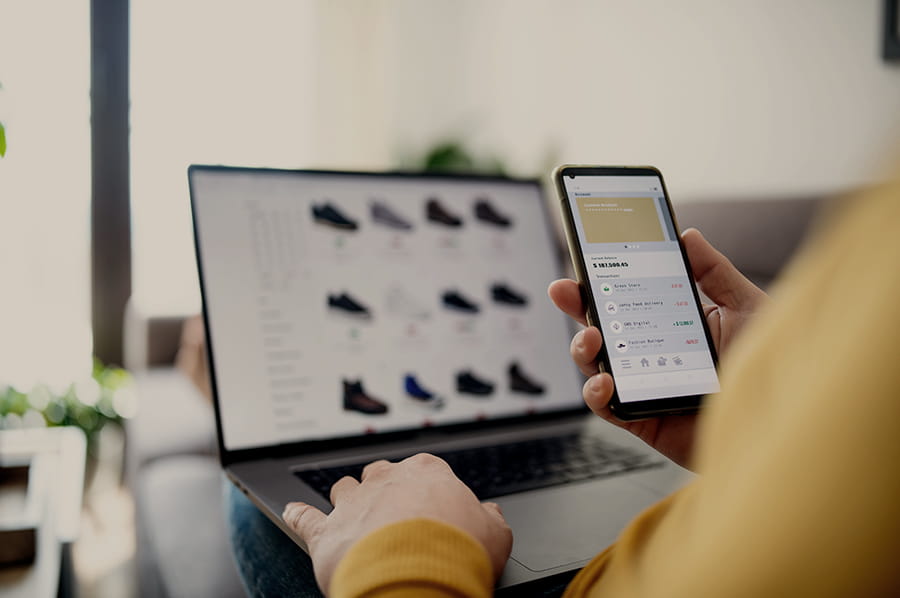 A person using a laptop and smart phone to shop online.