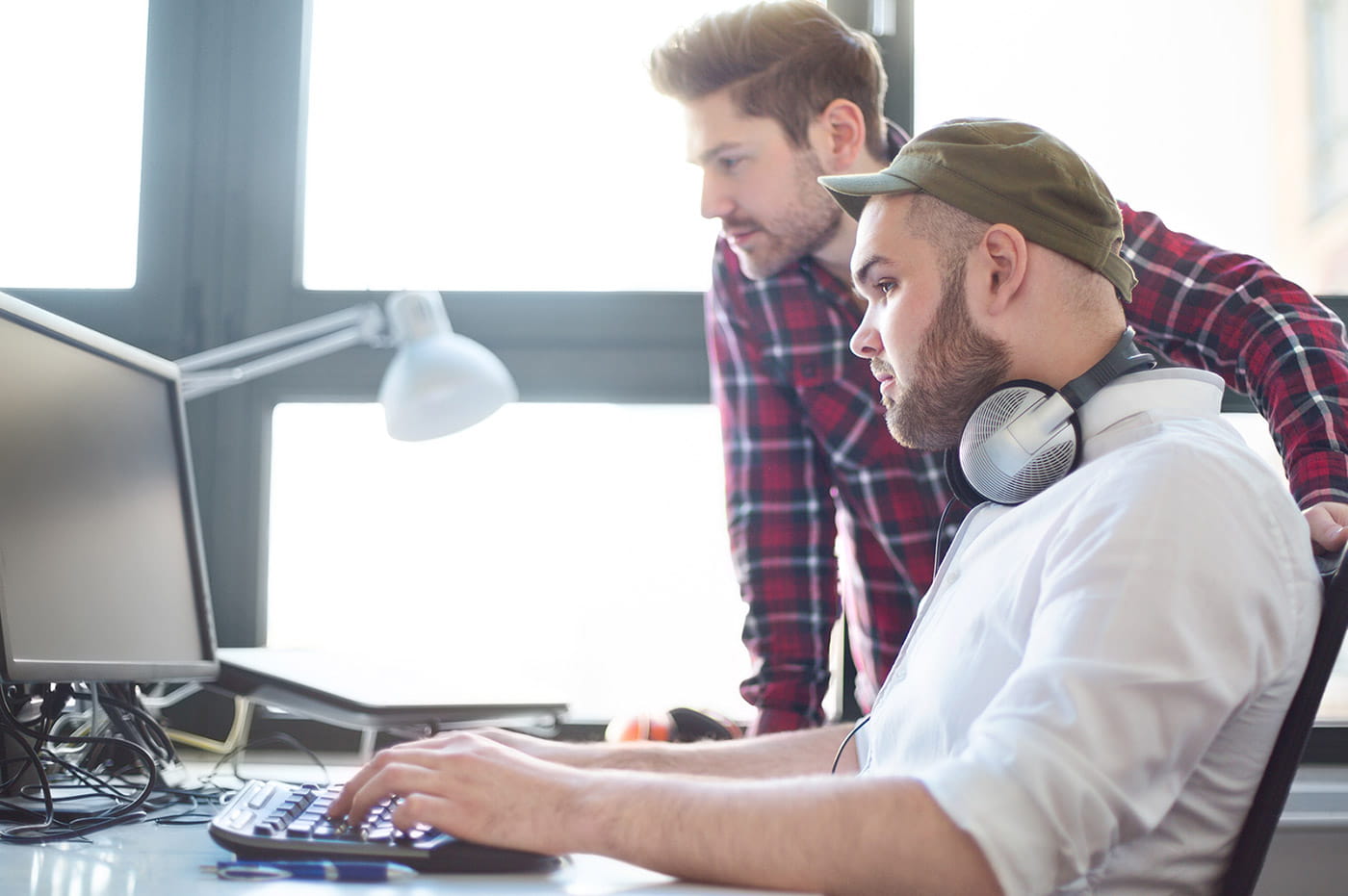 Two people working and looking at a desktop computer.