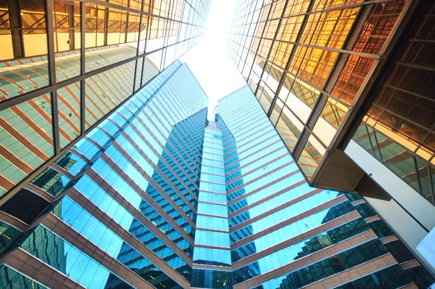 Several glass skyscrapers clustered together with sun shining through them.