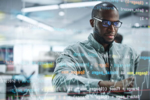 Man sitting in front of a computer with code going across the screen.