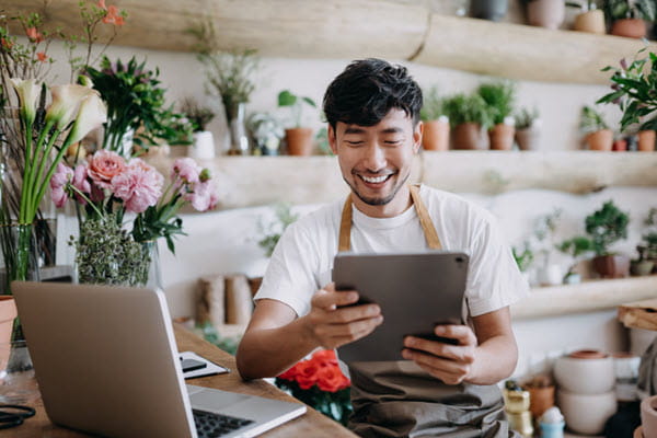 A florist using a tablet in his flower shop.