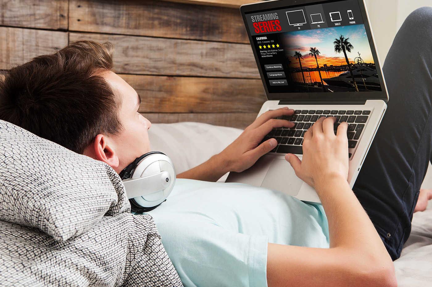 A man using a streaming service on a laptop device sitting on a couch